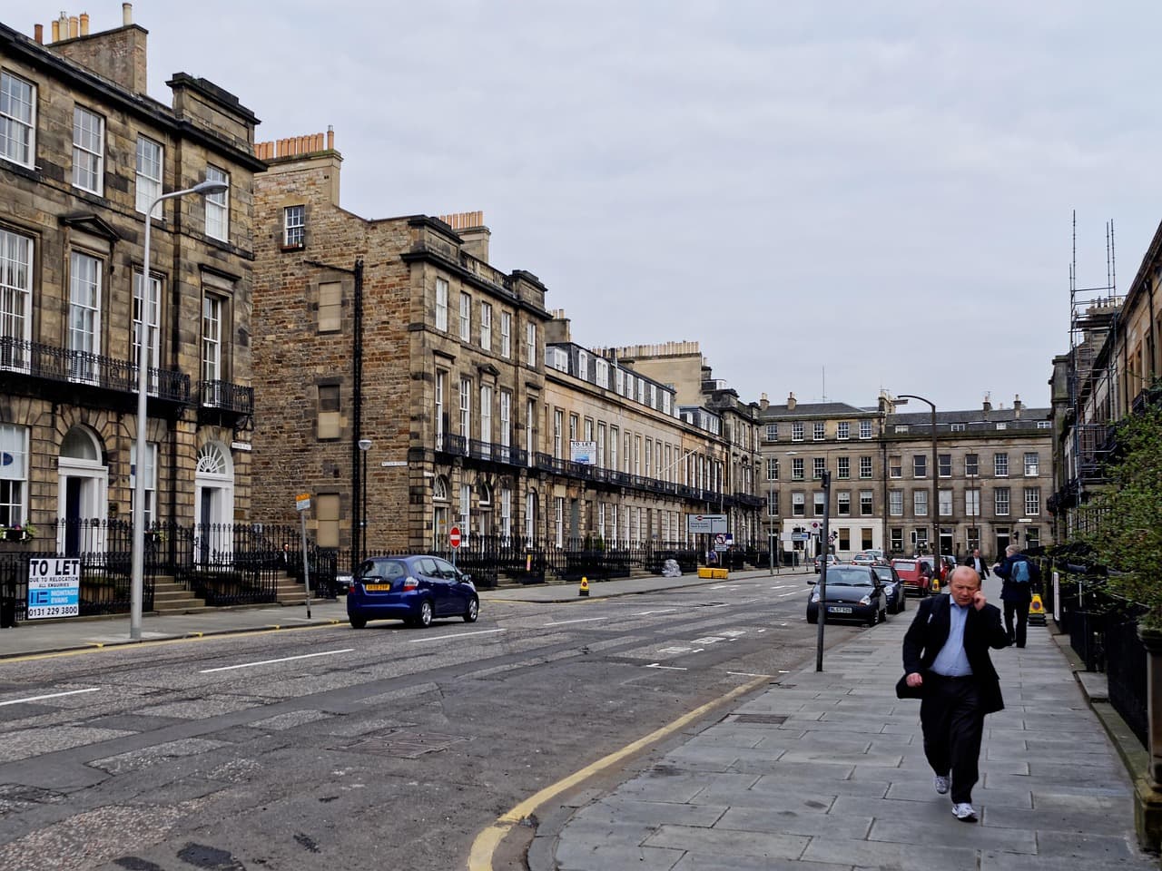 A New Town street in Edinburgh: sandstone terraces, black railings and parked cars